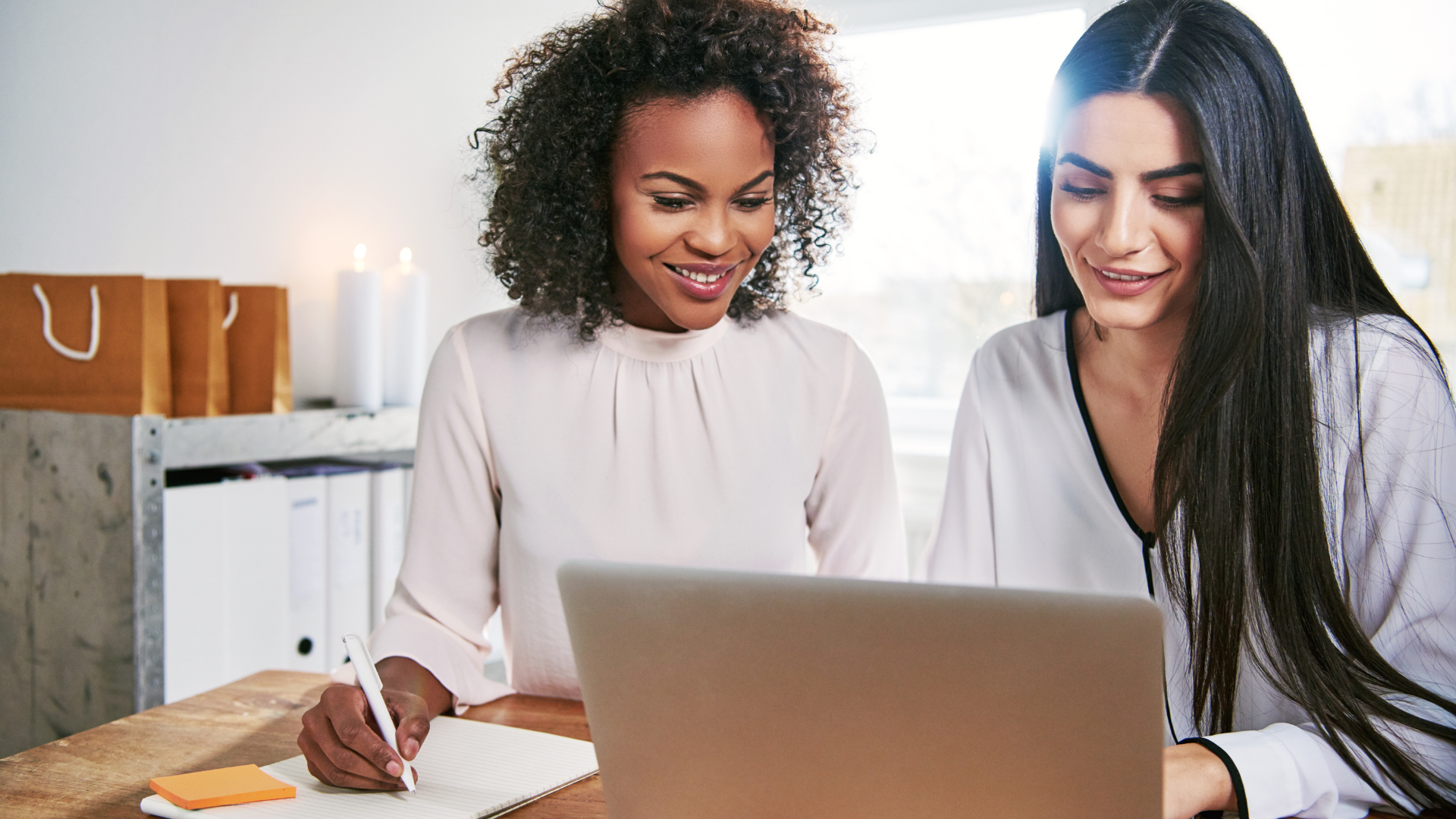 Two young business partners looking at a laptop and discussing incorporating their business: