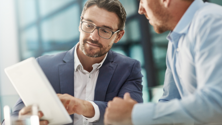 An image of two business partners discussing a holding company they have set up for their small business.