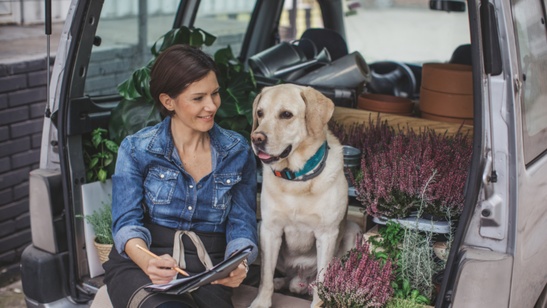 A self Employeed business person sitting in her vehicle with her golden lab.